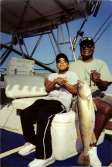 Father and son sitting together on charter boat with trophy fish in hand.