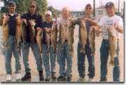 The group holds out fish in each hand for the camera.